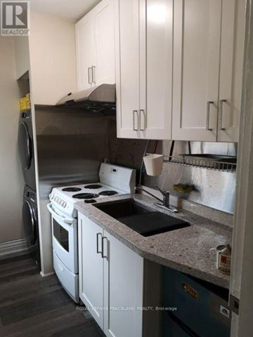 Toronto (South Riverdale) apartment for rent - A kitchen with white cabinets and a black stove top.