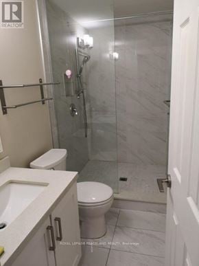 Toronto (South Riverdale) apartment for rent - A white toilet sits in a bathroom with a glass shower stall.