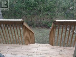 Markham (Unionville) townhouse for rent - A wooden deck with a railing and steps leading to a grassy area.