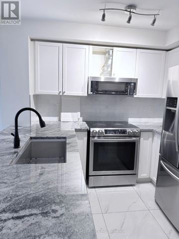Mississauga (Churchill Meadows) townhouse for rent - A modern kitchen with stainless steel appliances and white cabinetry.