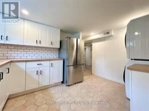 Niagara Falls (Hospital) apartment for rent - A kitchen with white cabinets and a tiled backsplash.