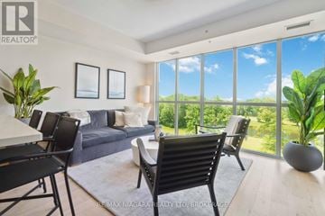 Niagara Falls (Oldfield) condo for rent - A living room with a couch, chairs, and a table with a vase of flowers on it.
