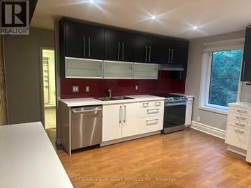 Toronto (The Beaches) apartment for rent - A kitchen with black cabinets and a red backsplash.