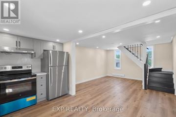 Brighton triplex for rent - A kitchen with a stove top oven, refrigerator, and a staircase.