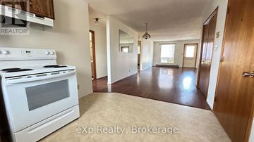 Quinte West (Trenton Ward) fourplex for rent - A kitchen with a white stove and a large open space.