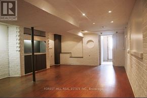 Toronto (Little Portugal) apartment for rent - A spacious room with wood flooring and white brick walls.