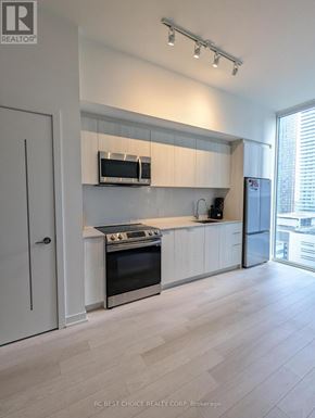 Toronto (Waterfront Communities) condo for rent - A modern kitchen with white cabinets and stainless steel appliances.