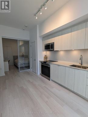 Toronto (Waterfront Communities) condo for rent - A modern kitchen with white cabinets and a wooden floor.