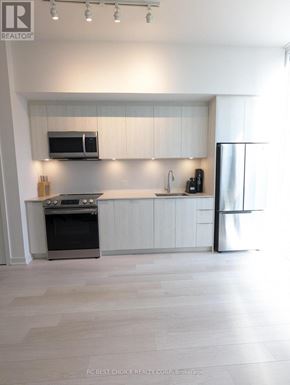 Toronto (Waterfront Communities) condo for rent - A modern kitchen with white cabinets and stainless steel appliances.