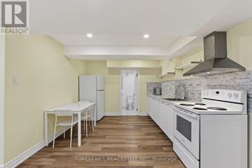 Vaughan (Beverley Glen) apartment for rent - A kitchen with a table and chairs in the foreground and a stove top oven in the background.