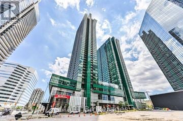 Toronto (Lansing-Westgate) condo for rent - A modern glass building stands tall among other skyscrapers on a sunny day.