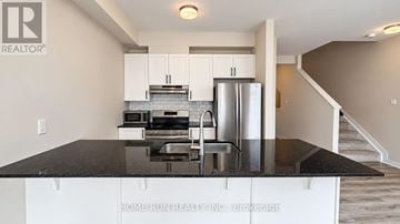 Ottawa townhouse for rent - A kitchen with white cabinets and a black countertop.