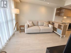 Toronto (Flemingdon Park) condo for rent - A living room with a couch, a lamp, and a kitchen area in the background.
