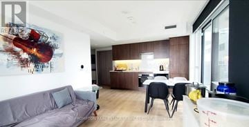 Toronto (Waterfront Communities) condo for rent - A modern living room with a grey couch and a painting of a violin on the wall.