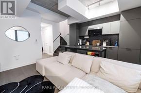 Toronto (Moss Park) townhouse for rent - A modern living room with a white couch and a black and white rug.