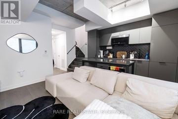 Toronto (Moss Park) townhouse for rent - A modern living room with a white couch and a black and white rug.