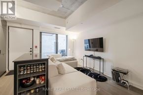 Toronto (Moss Park) townhouse for rent - A living room with a couch, a television, and a cabinet with bottles on it.