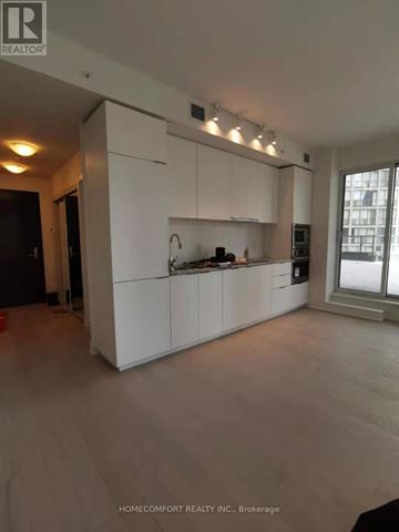 Toronto (Bay Street Corridor) condo for rent - A white kitchen with wooden floors and a window.
