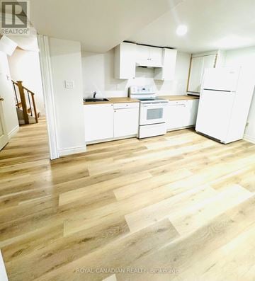 Ajax (Central) apartment for rent - A kitchen with white appliances and wooden floors.