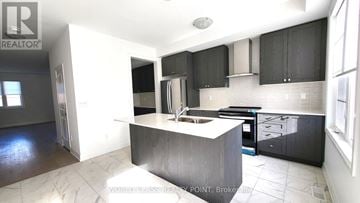 Whitby (Port Whitby) townhouse for rent - A kitchen with black cabinets and a white island.