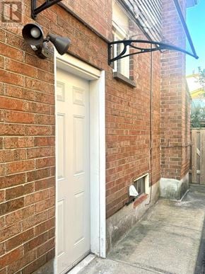 Toronto (Milliken) apartment for rent - A white door is on the left side of a brick wall.