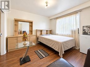 Toronto (Oakridge) triplex for rent - A bedroom with a bed, a dresser, and a mirror.