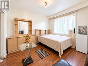 Toronto (Oakridge) triplex for rent - A bedroom with a bed, dresser, and mirror.