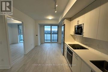 Oshawa (Windfields) condo for rent - A well-lit kitchen with white cabinets and a view of the city through the windows.