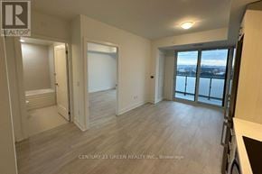 Oshawa (Windfields) condo for rent - A spacious room with wooden flooring and a view of the city through the windows.