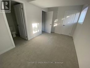 Cambridge townhouse for rent - A realtor photo of a white bedroom with a door open to a bathroom.