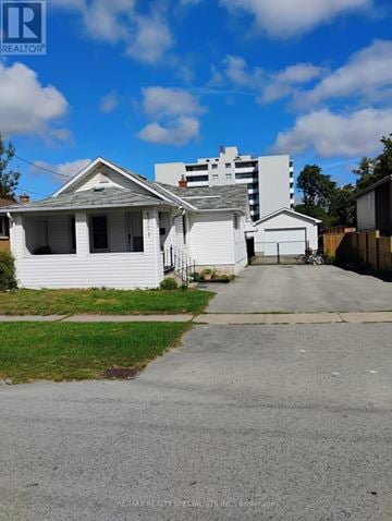 Niagara Falls (Morrison) apartment for rent - A white house with a grey roof is in front of a multi-story building.