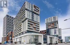 Markham (Unionville) condo for rent - A modern multi-story building with a glass entrance and a car parked in front.