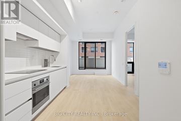 Toronto (Thorncliffe Park) condo for rent - A white kitchen with a stove top oven and a wooden floor.
