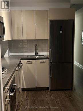 Toronto (Waterfront Communities) condo for rent - A kitchen with a black fridge and wooden floors.