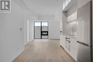 Hamilton (Corktown) condo for rent - A spacious kitchen with white cabinets and a refrigerator.