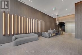 Hamilton (Corktown) condo for rent - A modern office lobby with a grey sofa and a long row of lights on the wall.