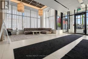 Toronto (Regent Park) condo for rent - A spacious lobby with a black and white rug, a brown sofa, and a glass door.