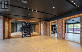 Toronto (Humber Heights) condo for rent - A spacious room with wooden floors and brick walls, furnished with a gym setup.