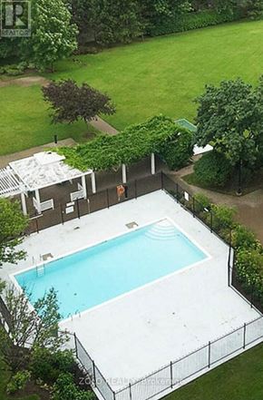 Mississauga (City Centre) condo for rent - A pool surrounded by a fence and trees.