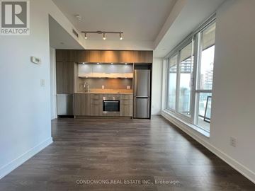 Toronto (Regent Park) condo for rent - A spacious kitchen with wooden cabinets and a large island.