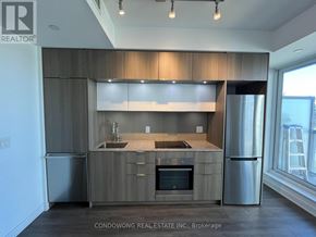 Toronto (Regent Park) condo for rent - A modern kitchen with wooden cabinets and stainless steel appliances.
