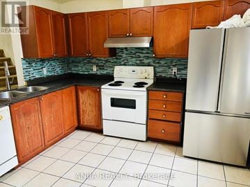 Toronto (Ionview) townhouse for rent - A kitchen with wooden cabinets and a stove top oven.
