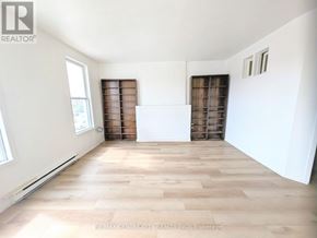 St. Thomas multi-family for rent - A room with wooden flooring and white walls, with a large window on the left and a door on the right.