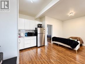 Toronto (Weston-Pellam Park) multi-family for rent - A small bedroom with a bed, a fridge, and a kitchenette.