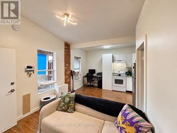 Toronto (Weston-Pellam Park) multi-family for rent - A living room with a couch and a kitchen area in the background.