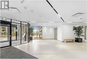 Toronto (Downsview-Roding-Cfb) condo for rent - A spacious lobby with a bench and a tree in a black planter.