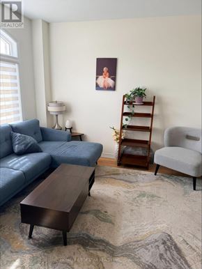 Otonabee-South Monaghan apartment for rent - A living room with a blue couch, a wooden coffee table, a grey armchair, a lamp, a plant, and a framed picture on the wall.