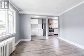 Toronto (O'connor-Parkview) apartment for rent - A spacious room with a white radiator on the left and a kitchen area visible through the open door.