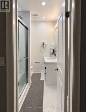 Toronto (Black Creek) apartment for rent - A bathroom with a glass shower door and white cabinetry.