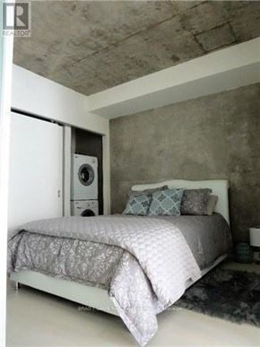 Toronto (Waterfront Communities) house for rent - A bedroom with a bed, pillows, and a washing machine in the corner.